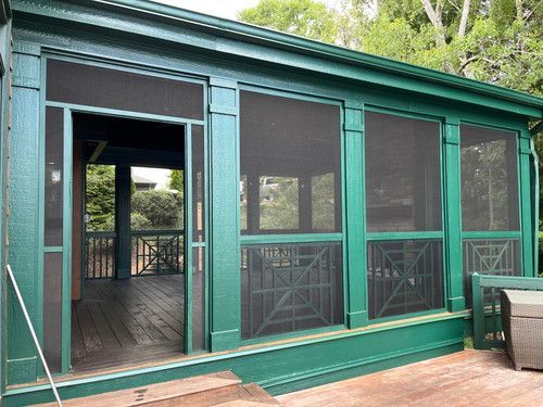 A green screened in porch with a wooden deck.