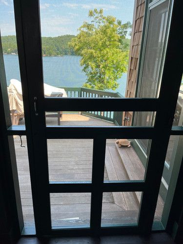 A screened in porch with a view of a lake.