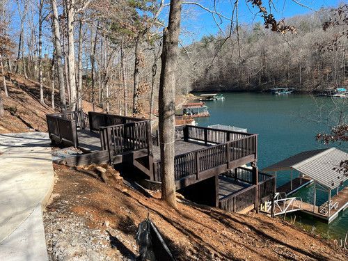 A large wooden deck overlooking a lake surrounded by trees.