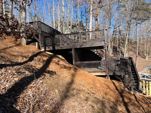 A large wooden deck is sitting on top of a hill in the woods.
