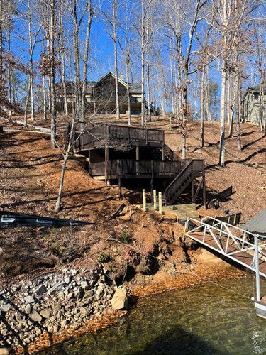 A house is sitting on top of a hill next to a body of water.
