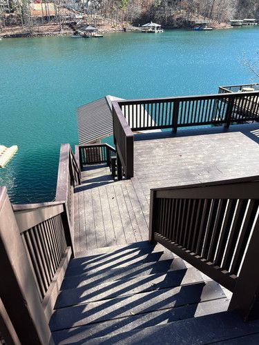 A wooden deck with stairs leading up to a lake.