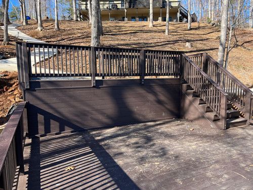A wooden deck with stairs leading up to it and a house in the background.