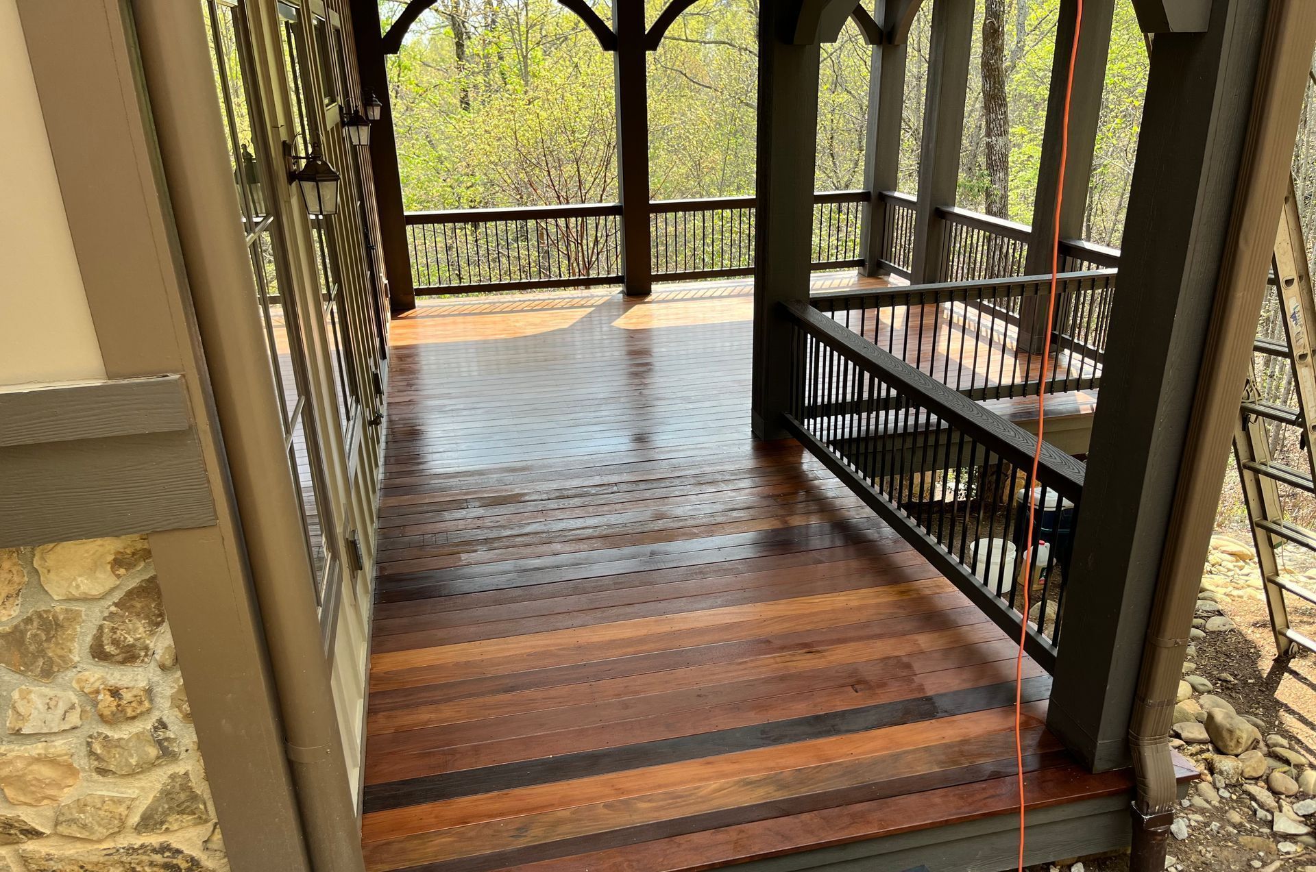 A wooden porch with a metal railing and stairs leading up to it.