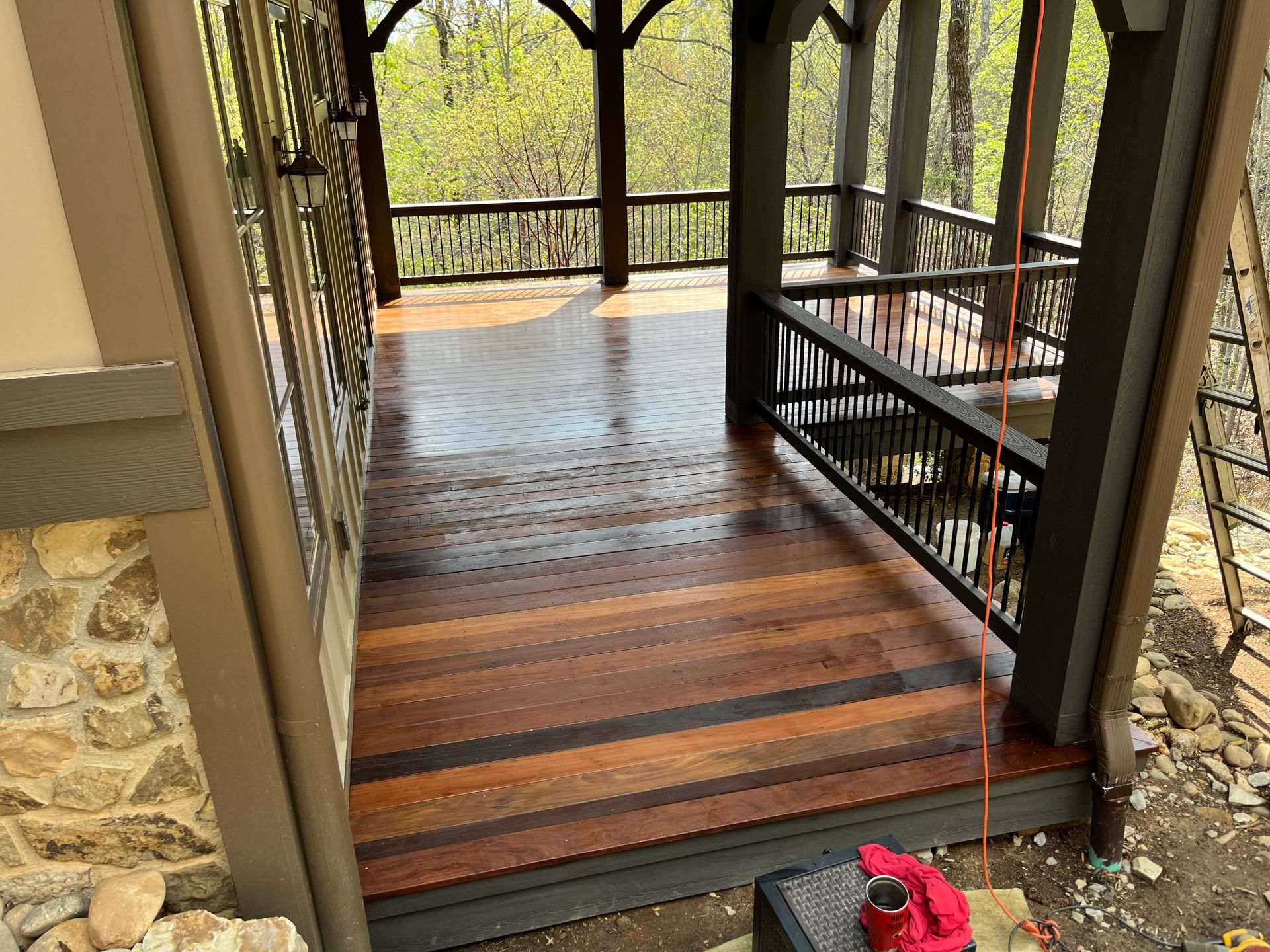 A porch with a wooden floor and a swing.
