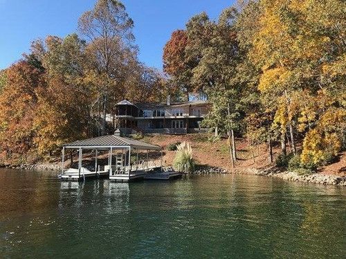 A house is sitting on the shore of a lake surrounded by trees.
