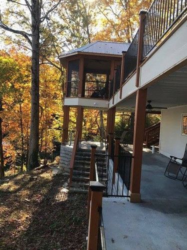 A large deck with a gazebo on top of it surrounded by trees.