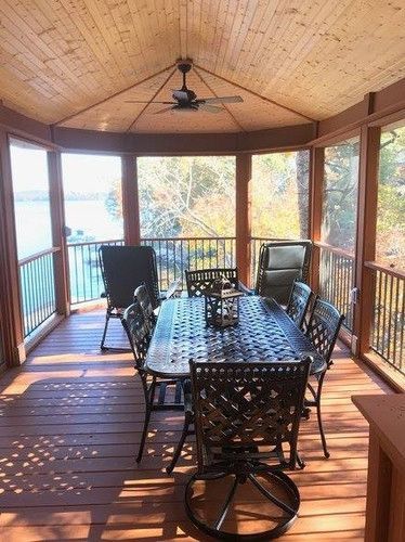 A screened in porch with a table and chairs and a ceiling fan.