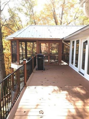A large deck with a screened in porch and trees in the background.