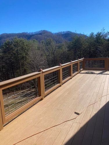 A large wooden deck with a fence and mountains in the background.