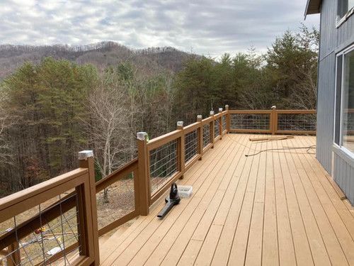 A large wooden deck with a view of the mountains and trees.
