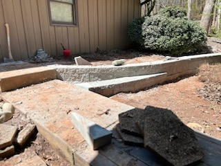 A pile of rocks is sitting on a wooden table in front of a house.