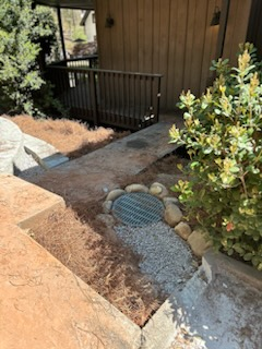A walkway leading up to a house with a manhole cover in the middle of it.
