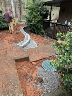 A man is working on a walkway in a backyard.
