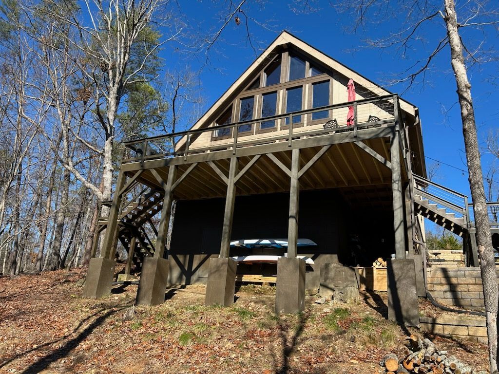 A small house with a large deck in the middle of a forest.