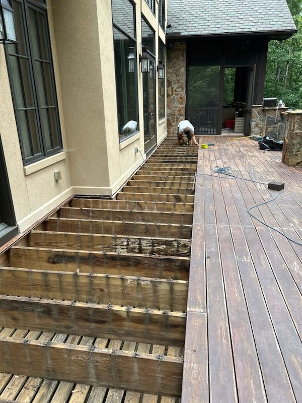 A man is working on a wooden deck in front of a house.