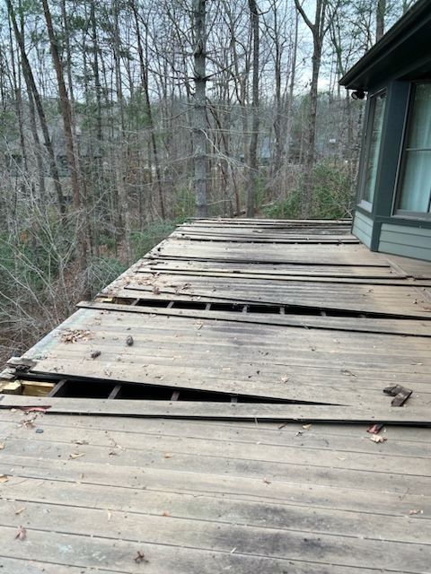 A broken wooden deck with a house in the background.