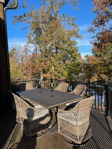 A patio with a table and chairs and trees in the background.
