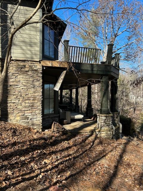 A house with a large deck on the side of it surrounded by trees.