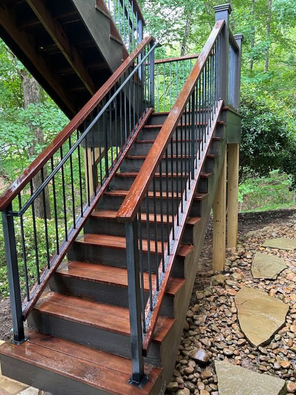 A set of wooden stairs with a metal railing leading up to a deck.