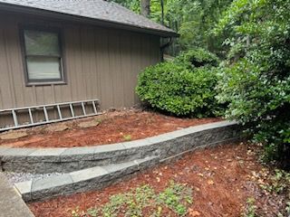 A house with a stone wall and a ladder in front of it.