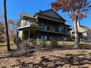 A large house is surrounded by trees and leaves on a sunny day.