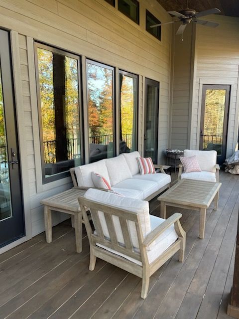 A porch with a couch , chairs , tables and a ceiling fan.