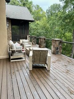 A wooden deck with a couch and chairs on it.