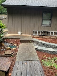 A wooden walkway leading to a house with a ladder in the backyard.