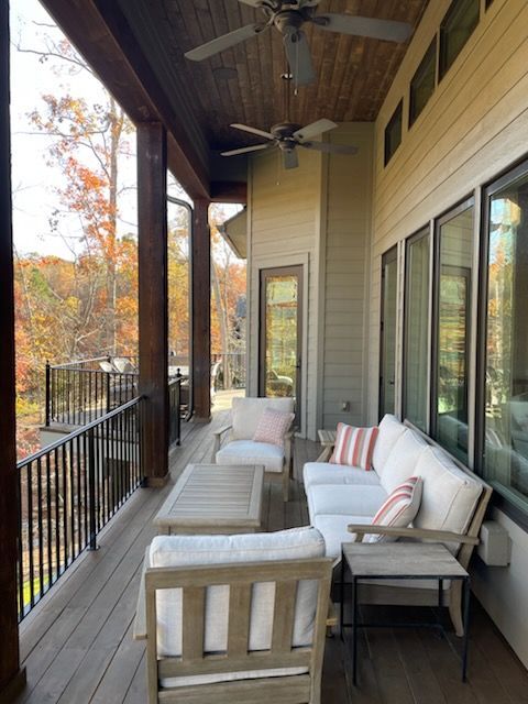 A porch with a couch and chairs and a ceiling fan