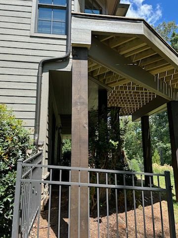 A house with a porch and a fence in front of it.