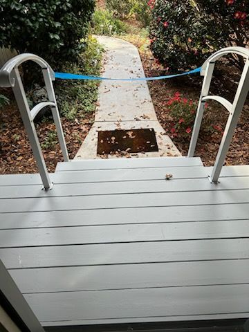 A wooden deck with stairs leading up to a concrete walkway.