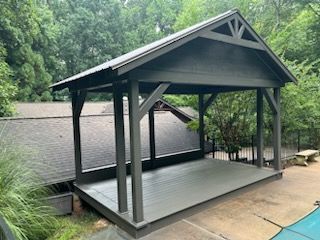 A large wooden pavilion is sitting next to a pool.