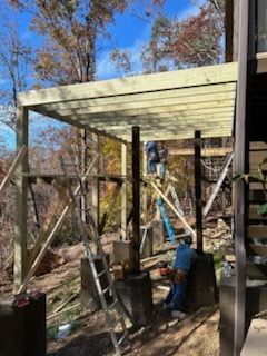 A man is standing on a ladder on top of a wooden deck.