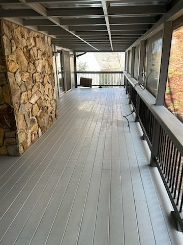 A long gray deck with a stone wall in the background.