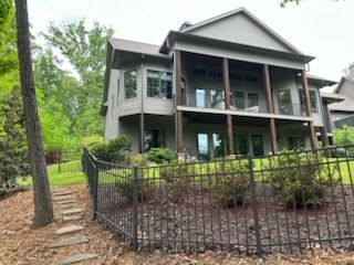 A large house with a fence around it is surrounded by trees.