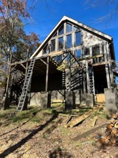 A large house with a lot of windows is being built in the woods.