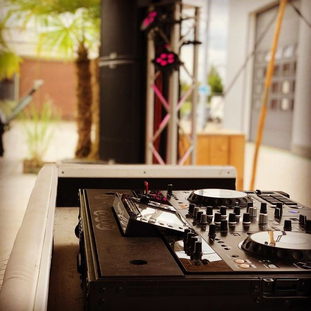 Een close-up van een dj-controller met een palmboom op de achtergrond