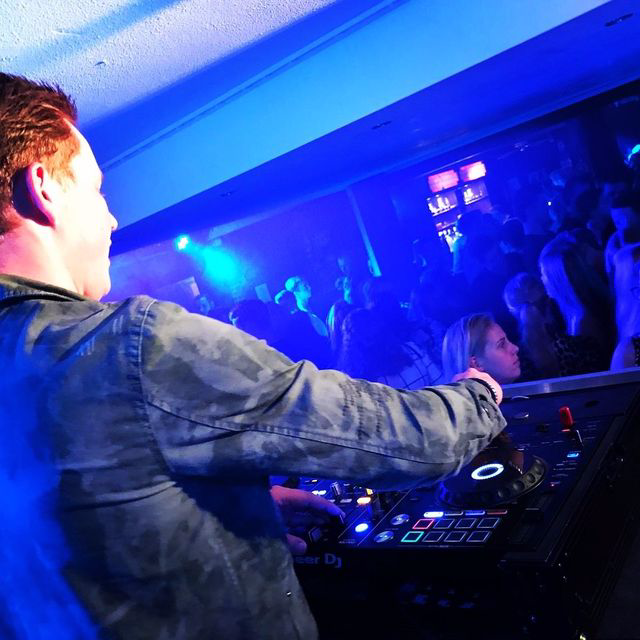 Een man in een camouflageshirt speelt muziek voor een publiek