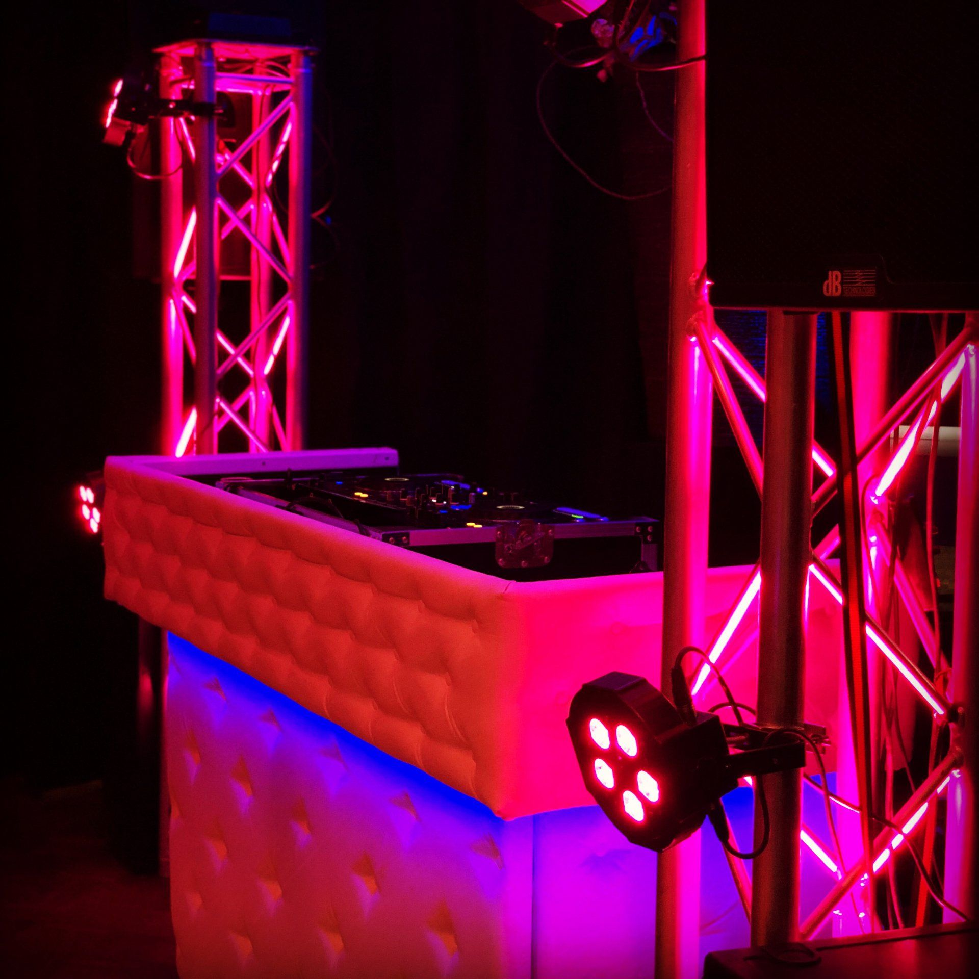 Een dj-booth is verlicht met roze en blauwe lichten.