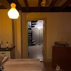 A glowing pendant light illuminates a kitchen area, with a spiral staircase visible through an open doorway.