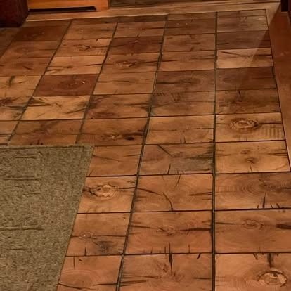 A light-brown floor featuring a pattern of square wood tiles with visible grain, knots, and cracks.