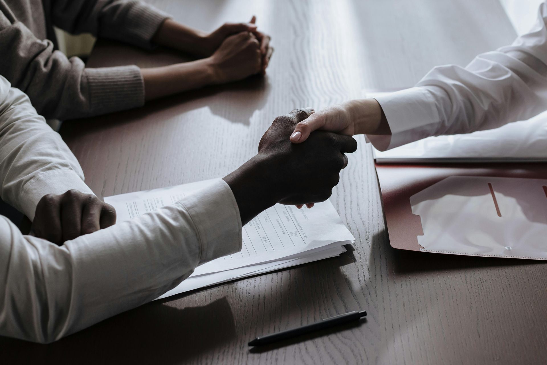 A man and a woman are shaking hands over a table.