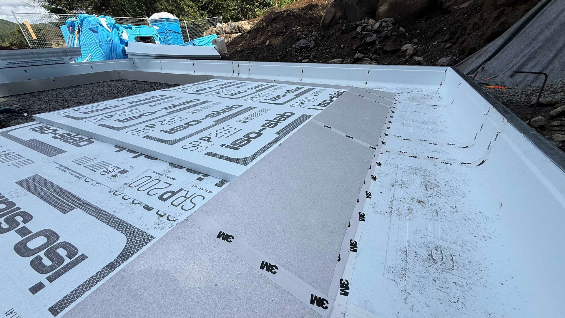 Chantier de construction de fondations avec panneaux d'isolation en mousse blanche.