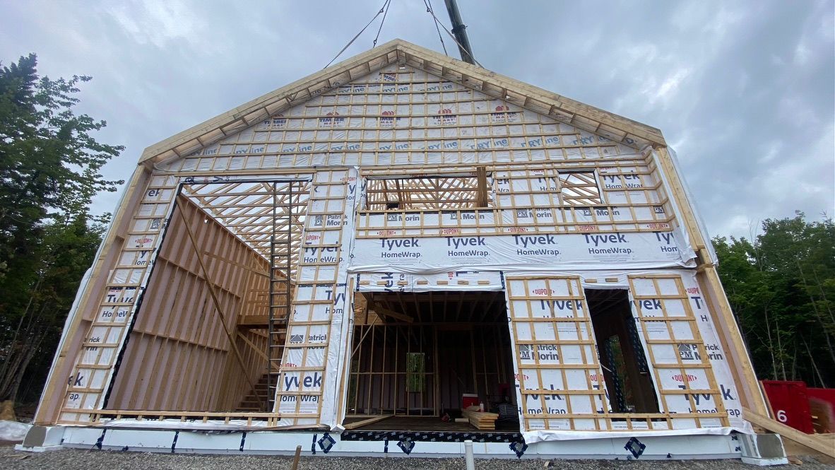 La structure en bois d'un bâtiment en construction, avec les cadres de portes et de fenêtres ouverts.