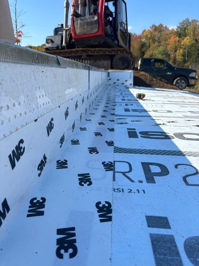 Chantier de construction avec excavatrice et camion noir ; mur isolé blanc et ruban adhésif 3M.