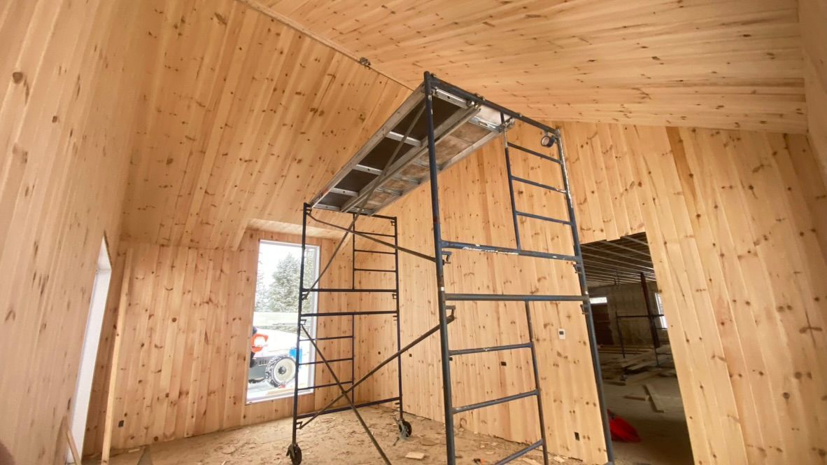 Intérieur d'une pièce en construction avec lambris et échafaudages.