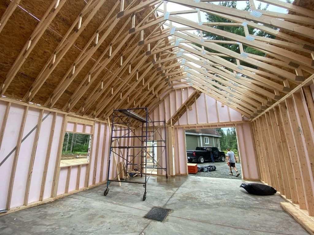 Vue intérieure d'un nouveau bâtiment à ossature bois en construction, avec charpente apparente et échafaudages.