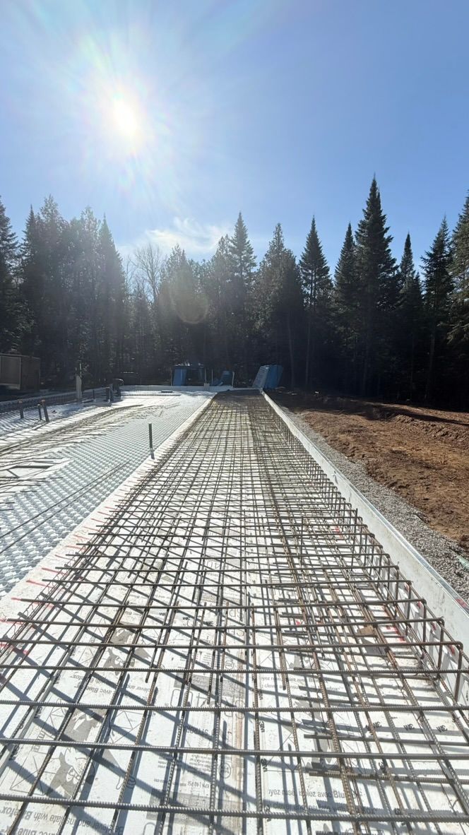 Treillis d'armature en acier préparé pour une fondation en béton, à l'extérieur, sous les arbres et en plein soleil.