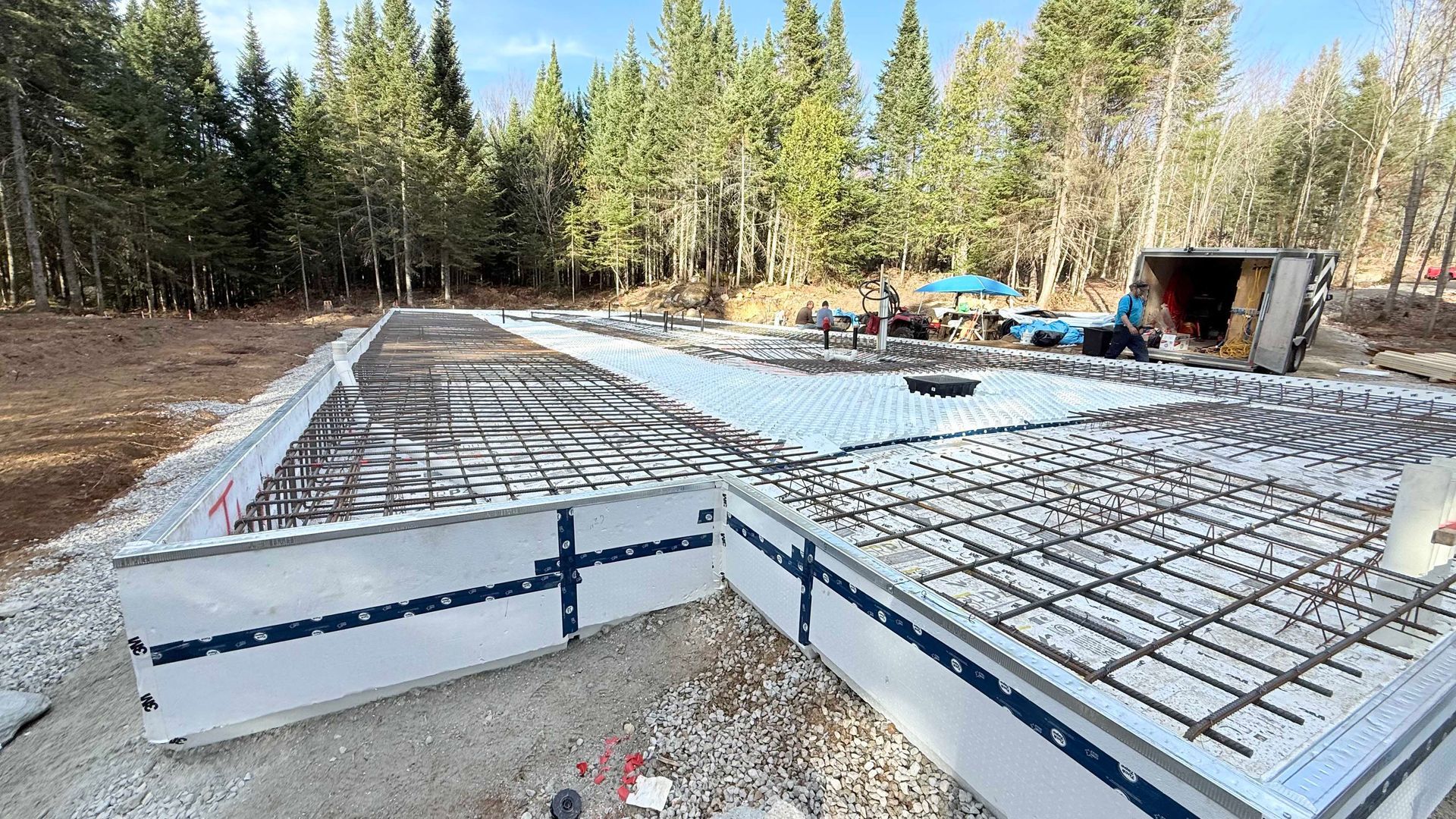 Structure de fondation en béton armé, préparée pour le coulage, dans une zone boisée.
